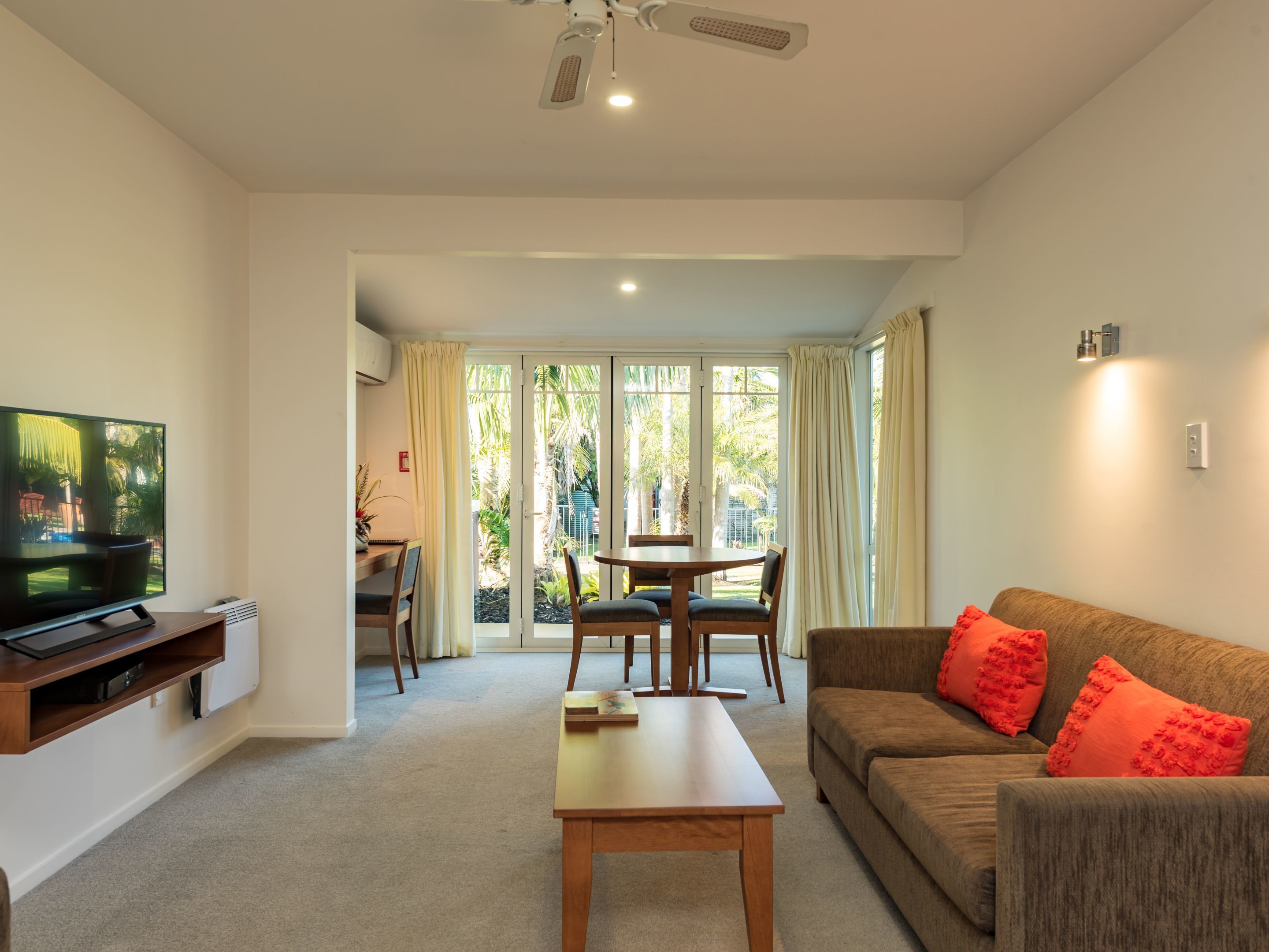 A living room with a television, a sofa, a coffee table, and a dining area with a table and chairs.