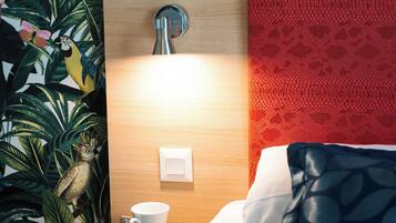 A hotel room with a wooden headboard, a white cup on a saucer, and a bed with a blue pillow.