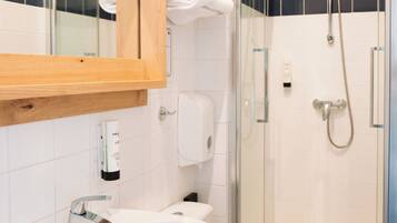 Un bagno con lavandino bianco, servizi igienici e cabina doccia in vetro.