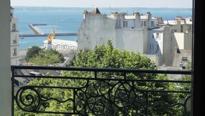 A balcony with a view of a coastal cityscape, including buildings and a pier. - Hotel Bellevue (Brest)
