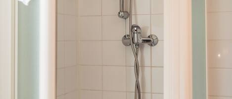 A shower with a handheld showerhead and a wall-mounted faucet.