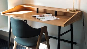 Escritorio en esquina con una silla, una lámpara y una revista sobre la mesa.