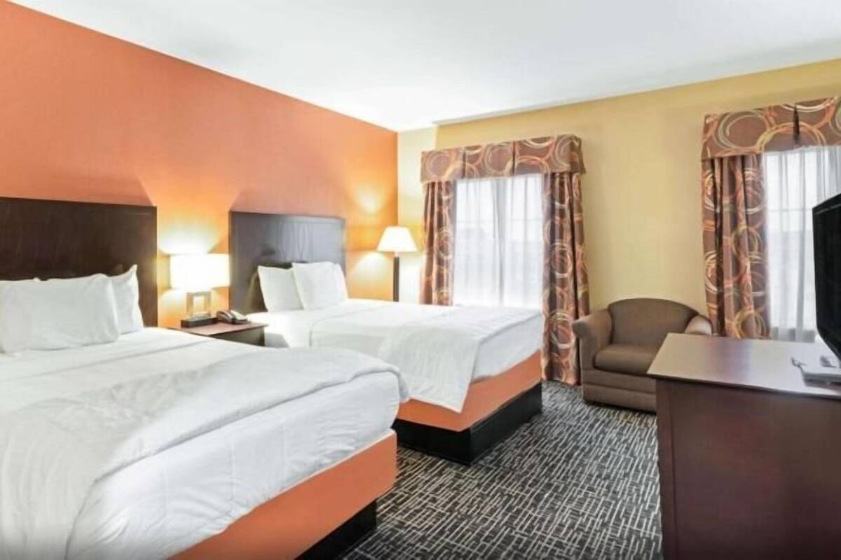 Une chambre d’hôtel avec deux lits, un bureau, une chaise et un téléviseur.