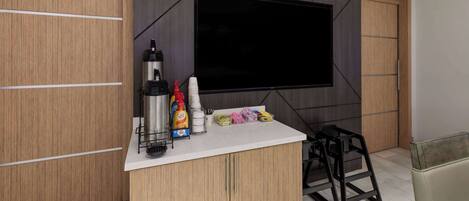 Una cocina moderna con televisor integrado, armarios de madera y encimera blanca.