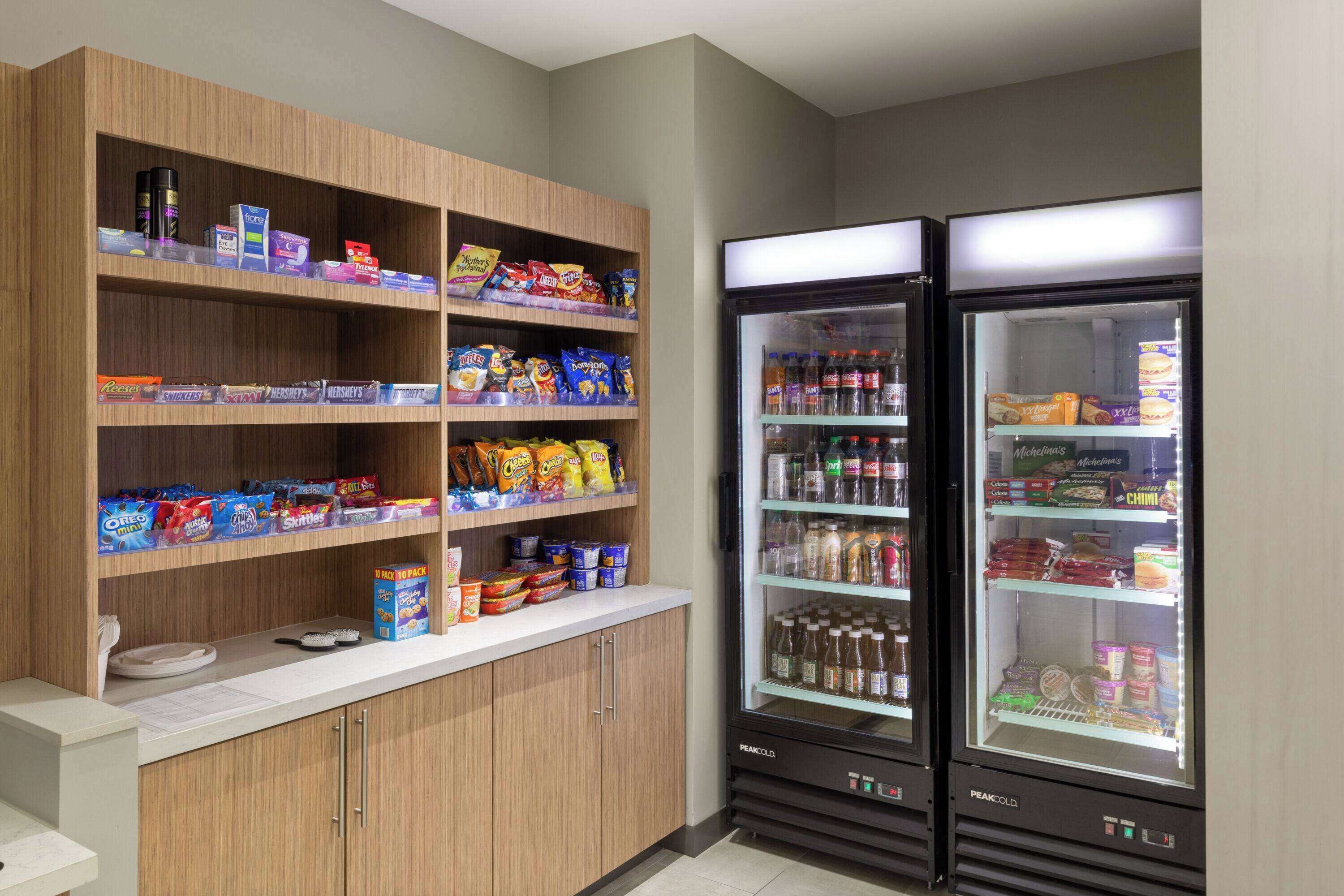 A vending area with snacks and beverages, including a refrigerator stocked with drinks and a shelf with various packaged goods.