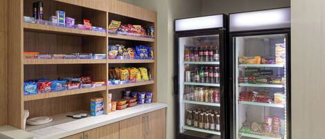 A vending area with snacks and beverages, including a refrigerator stocked with drinks and a shelf with various packaged goods.