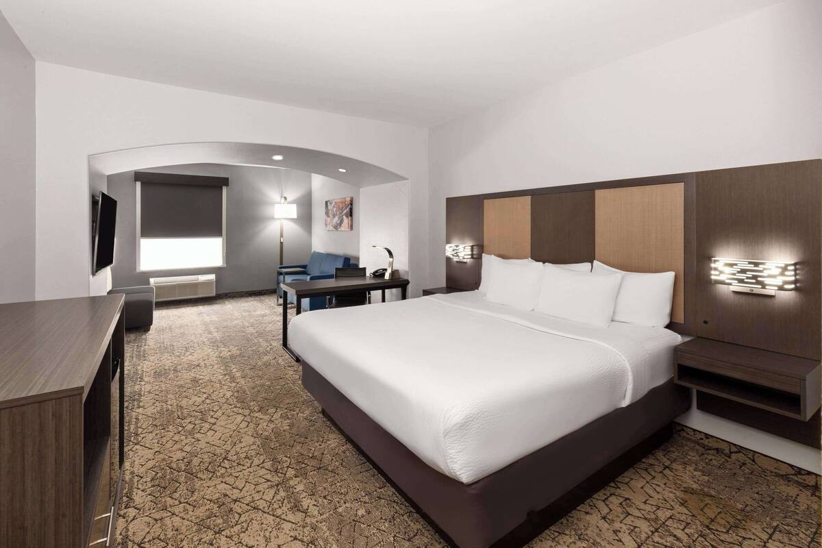 Une chambre d’hôtel avec un grand lit, un bureau, une chaise, une télévision et une lampe.
