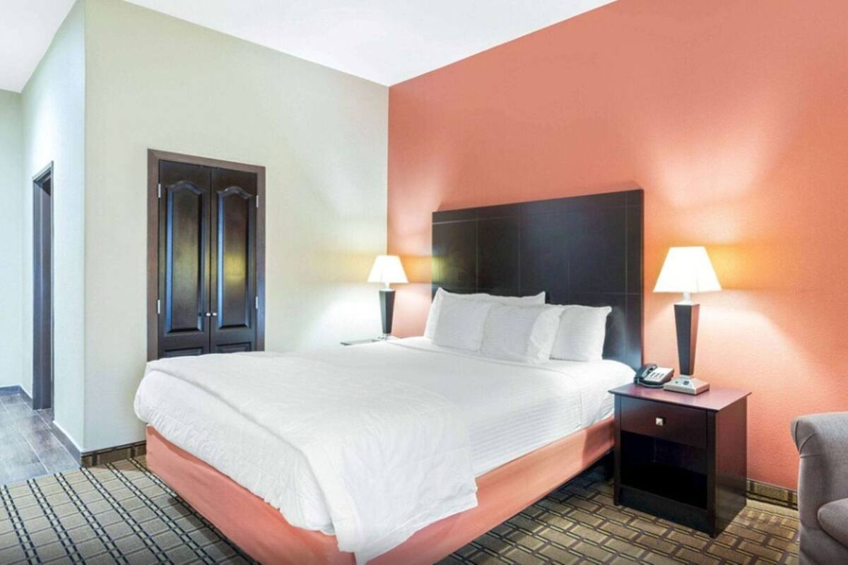 Une chambre d’hôtel avec un lit, des tables de chevet, une chaise et une porte.