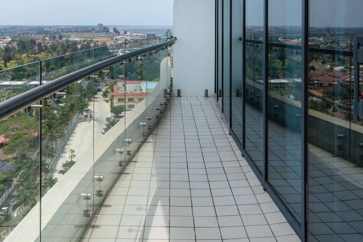 A balcony with a glass railing overlooking a cityscape.