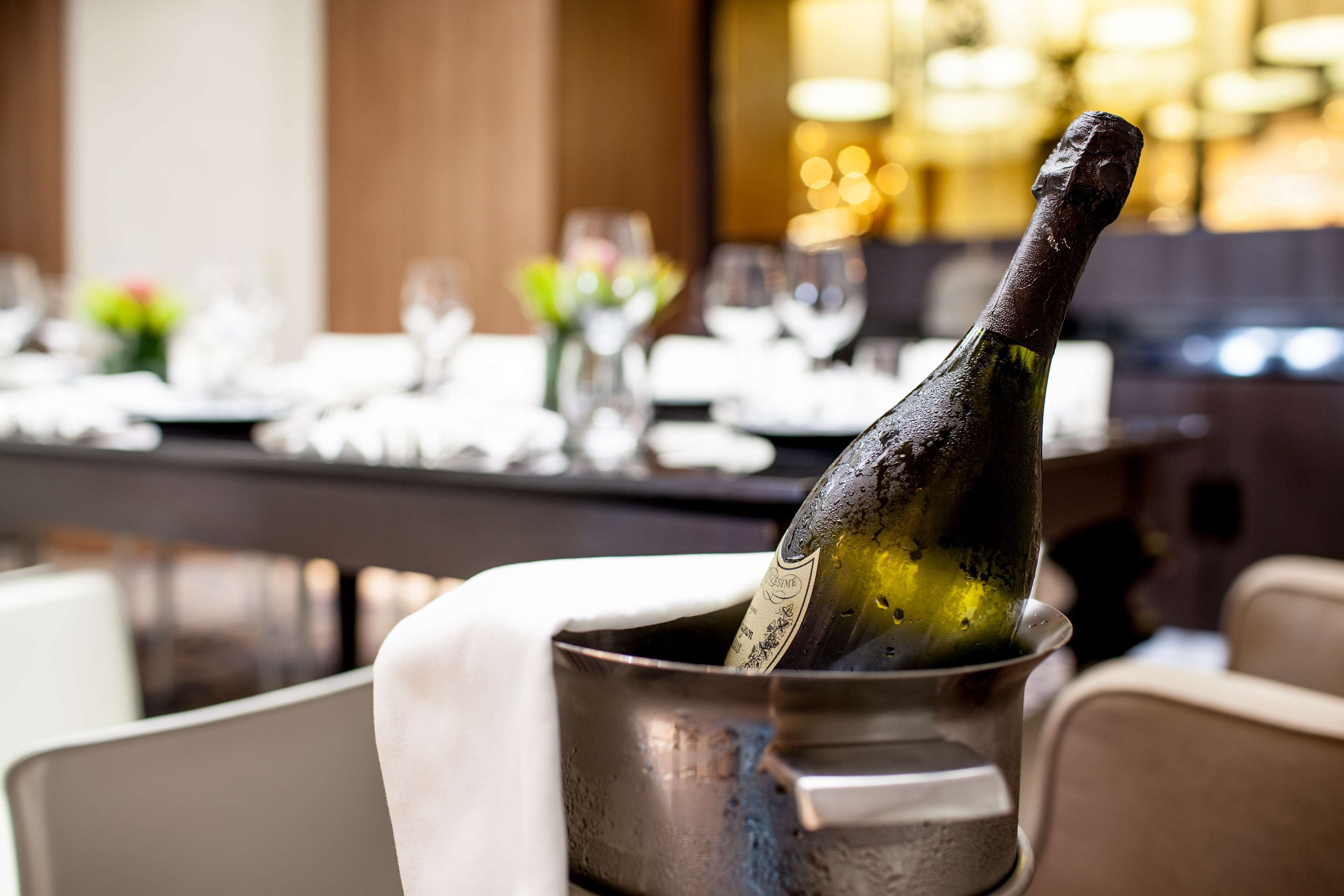 A bottle of champagne in a metal bucket on a table in a restaurant setting.