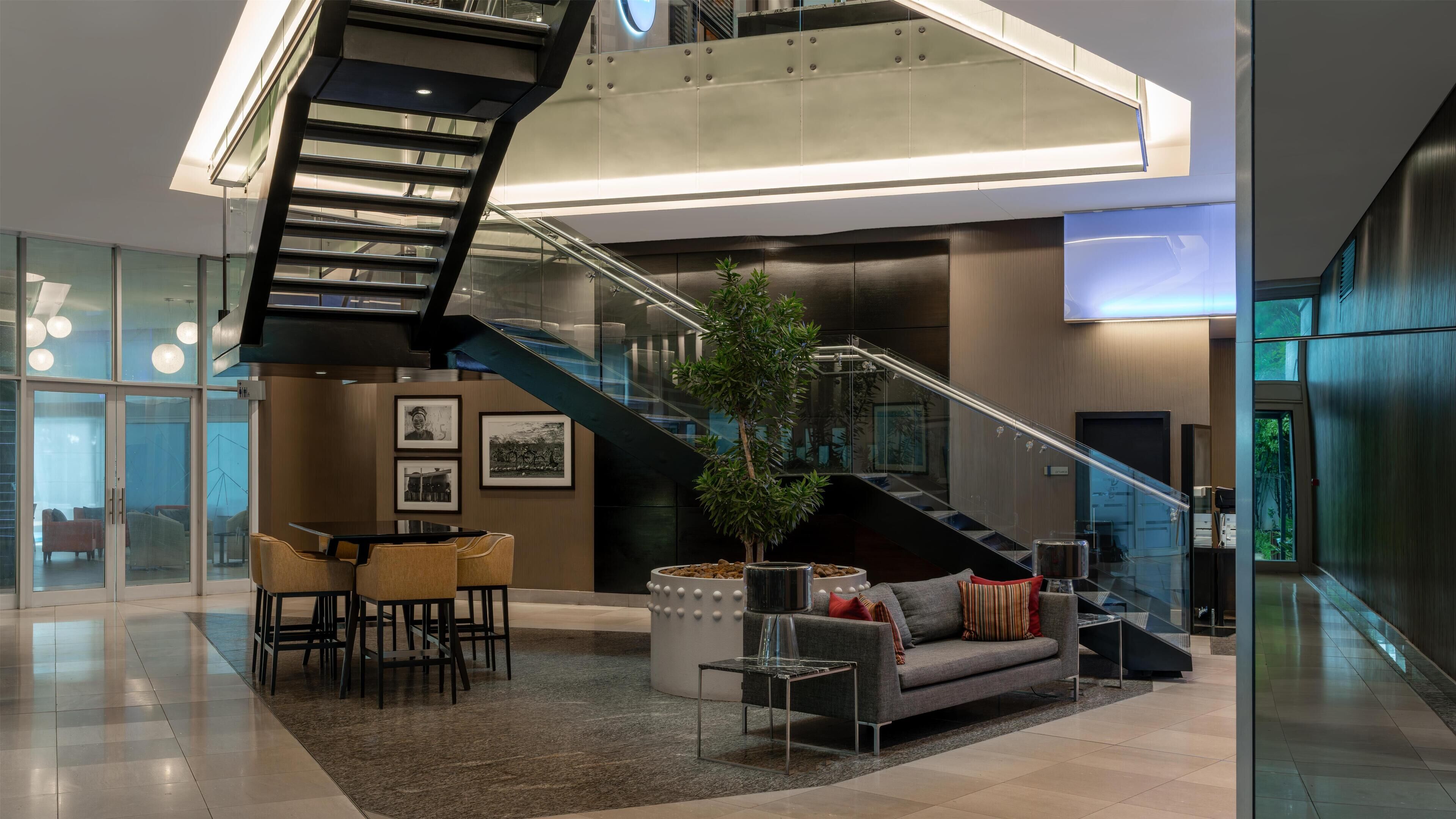 Eine moderne Lobby mit Treppe, Sitzgelegenheiten und einer Topfpflanze.