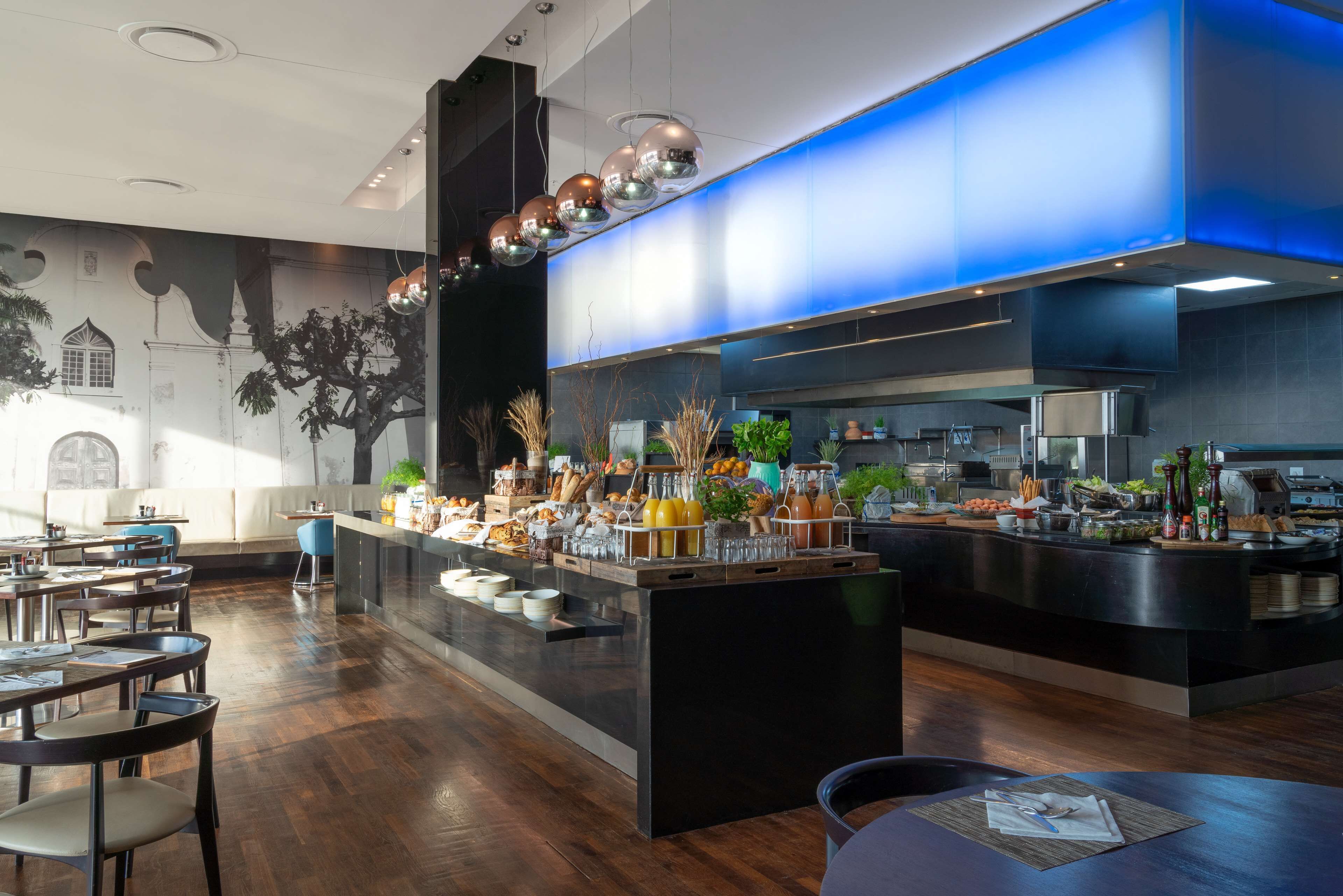 Un restaurante moderno con barra central, mesas y sillas de madera.
