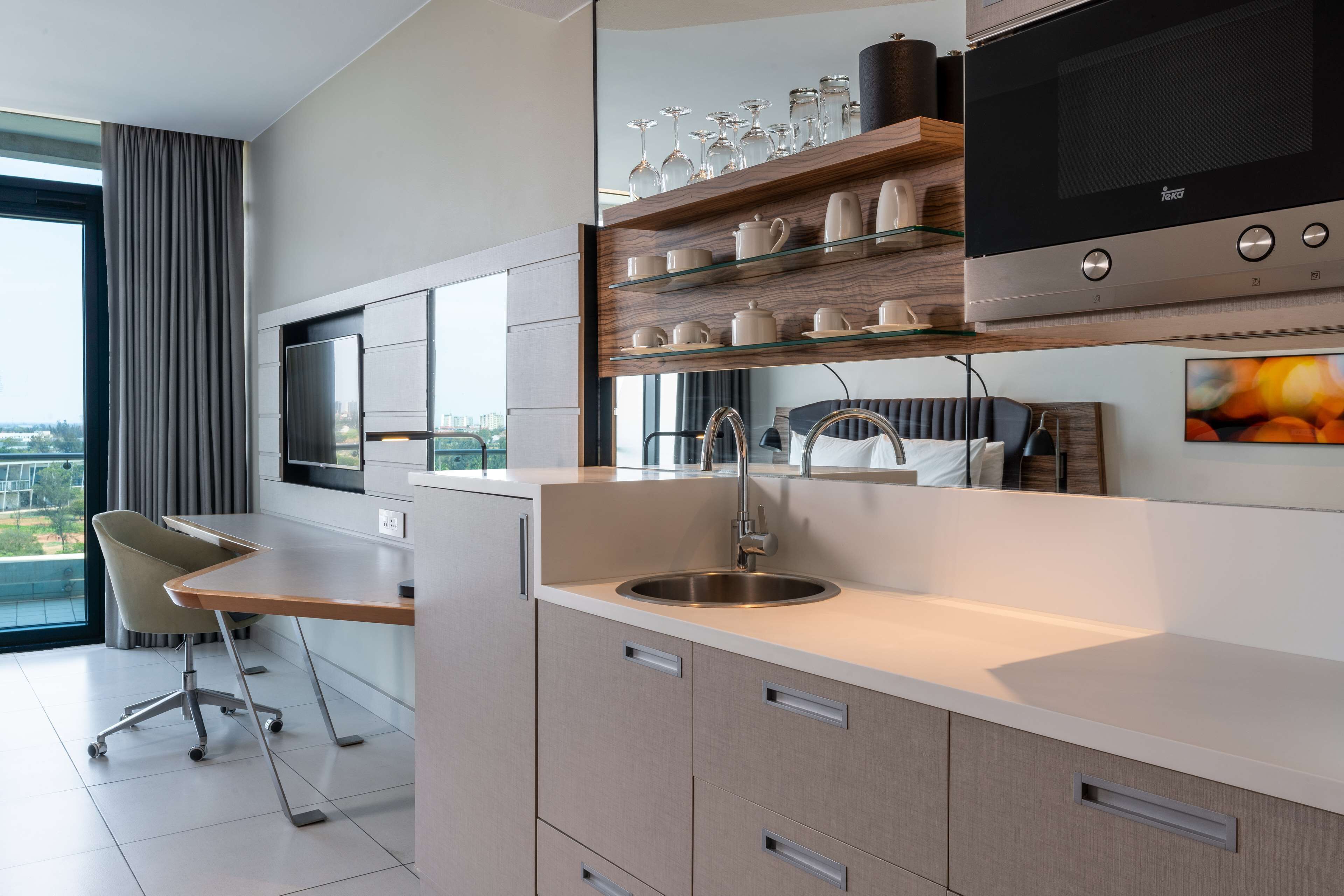 Una cocina moderna con horno empotrado, un ventanal grande y un comedor con una silla.