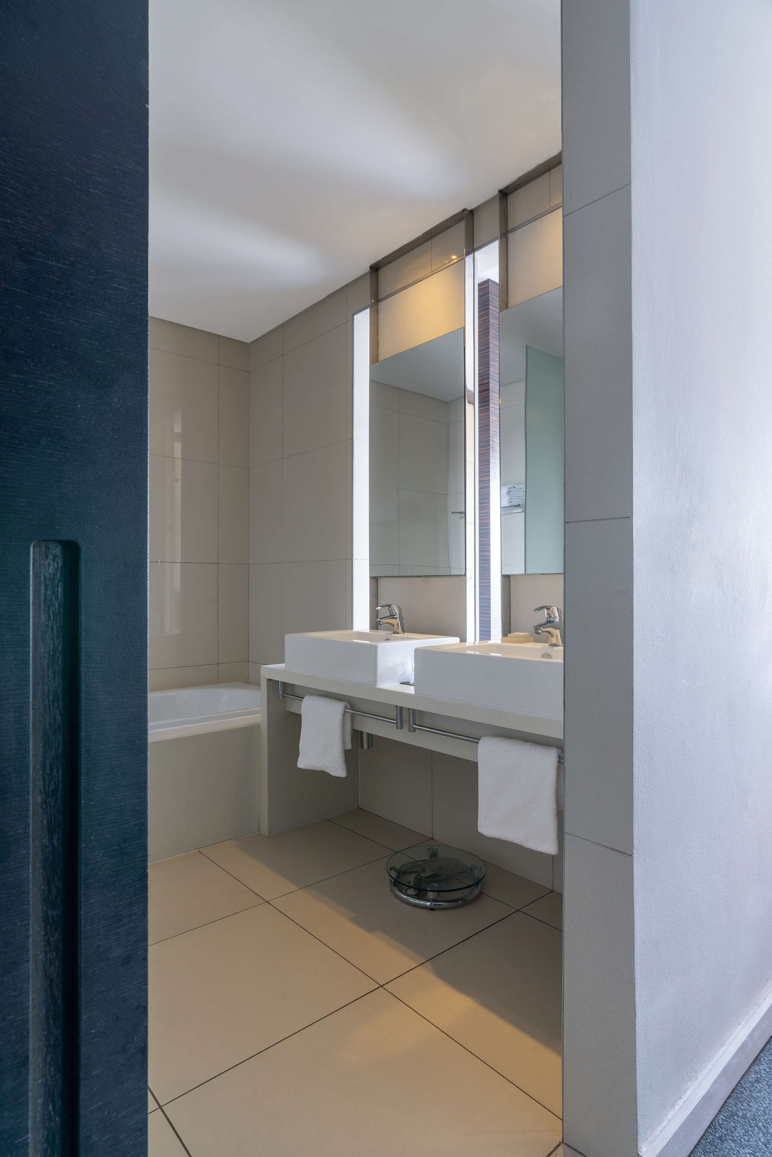Un baño moderno con dos lavamanos, un espejo grande y una bañera.