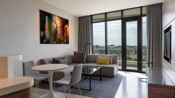 Una sala de estar moderna con sofá, sillones, una mesa de centro y un amplio ventanal con vistas a la ciudad.