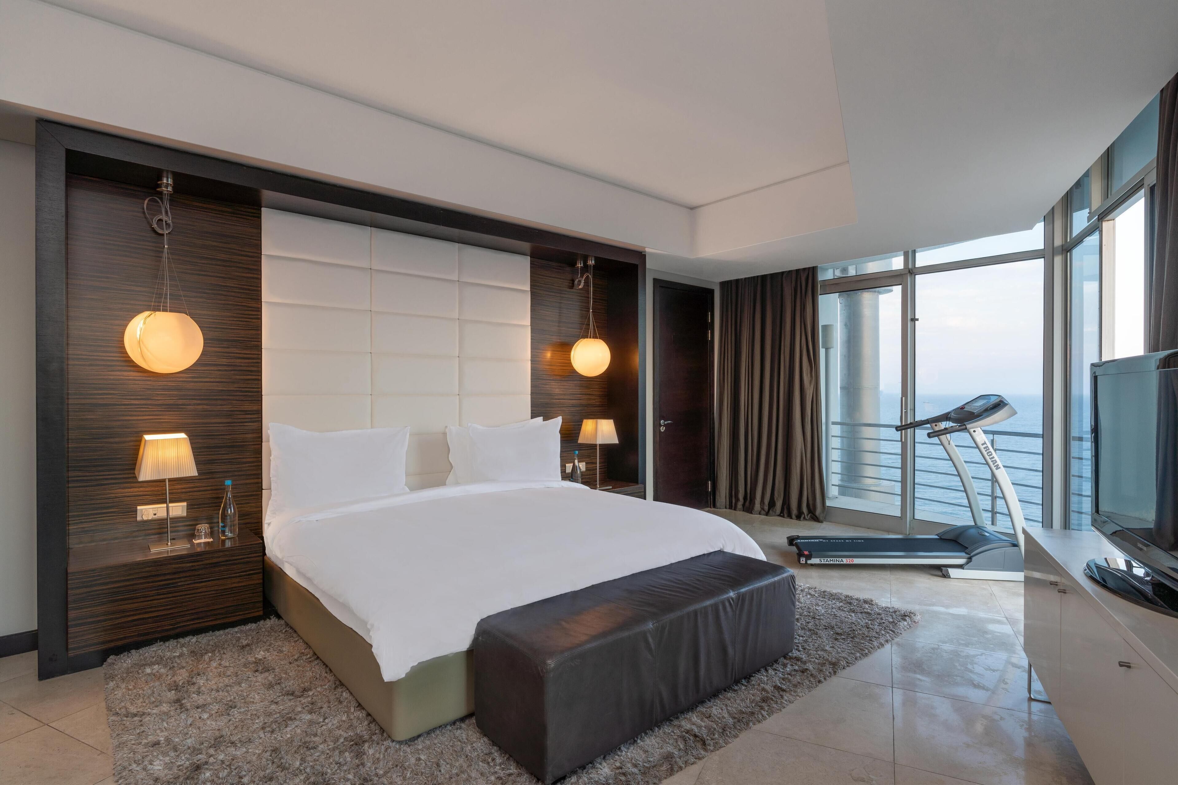 Una habitación de hotel moderna con una cama grande, una cinta de correr y un televisor.