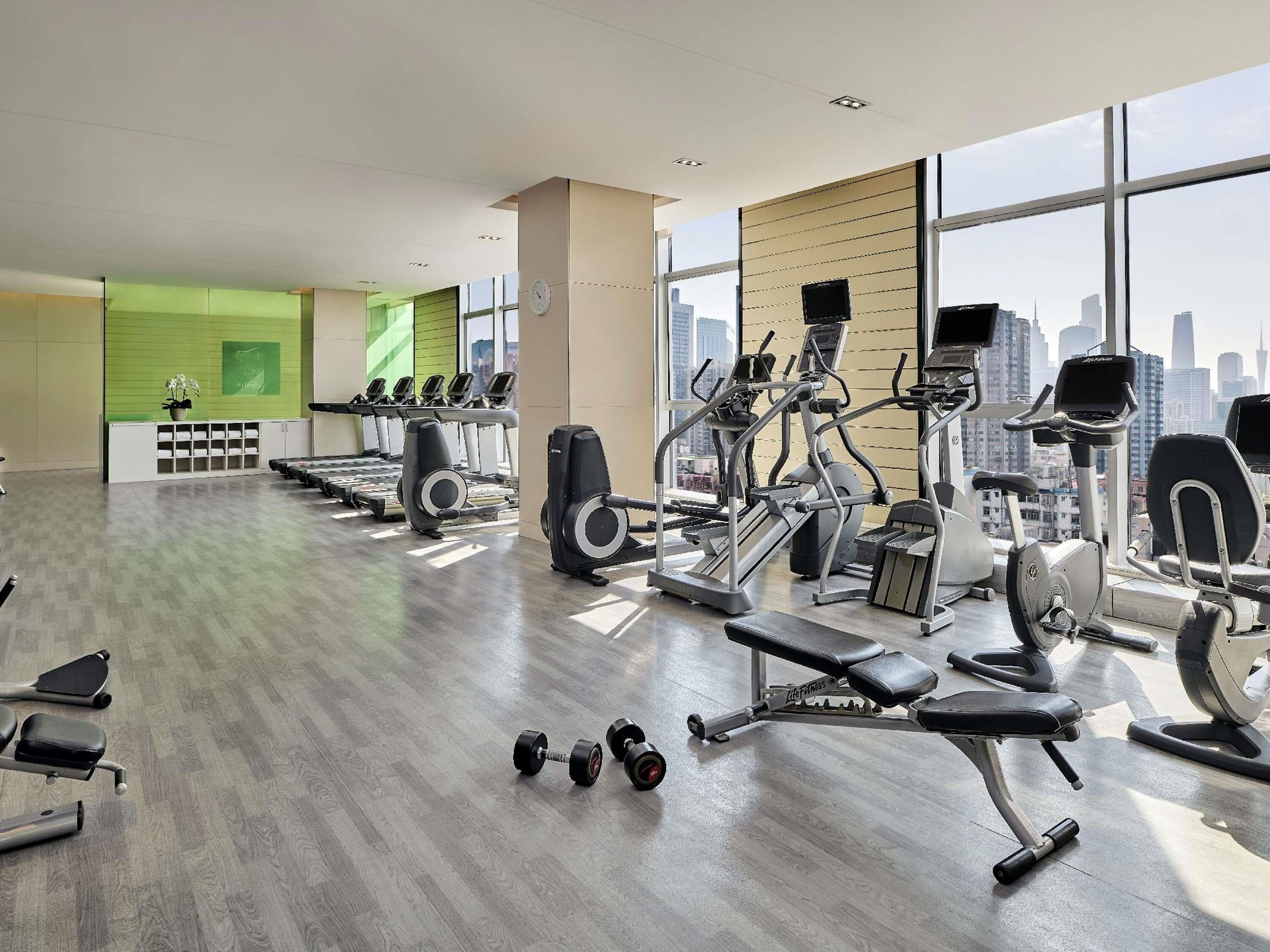 A gym with cardio machines, free weights, and a bench.