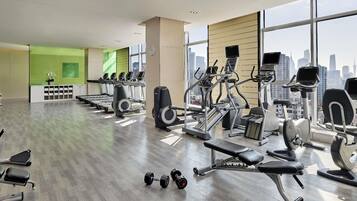 A gym with cardio machines, free weights, and a bench.