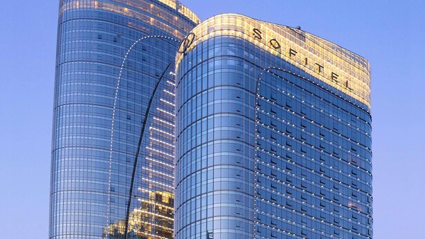 Dos edificios altos con fachadas de vidrio reflectante y la palabra 'SOFITEL' en la parte superior del edificio de la derecha.