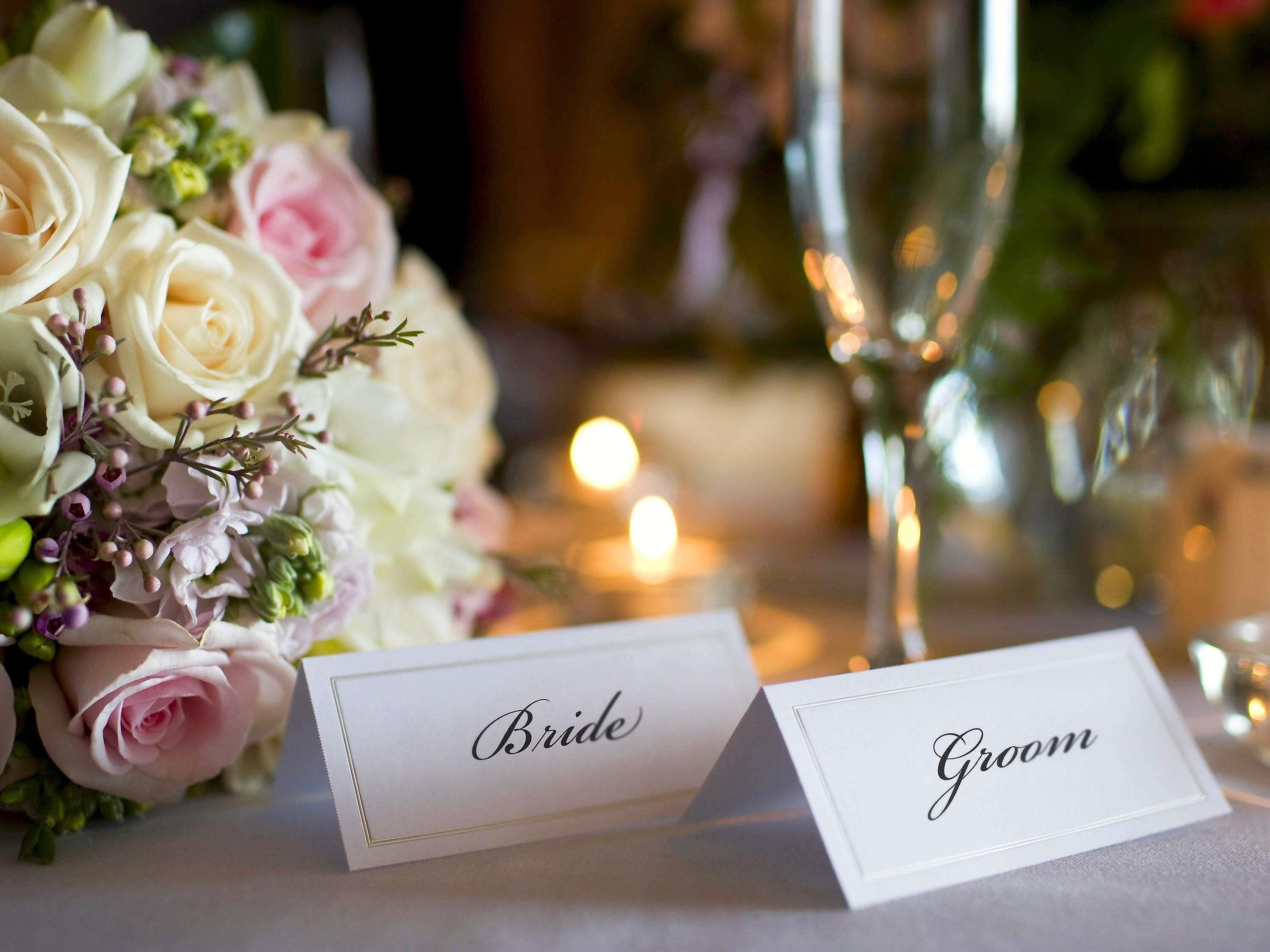 A table setting with a bouquet of flowers and name cards labeled 'Bride' and 'Groom.'