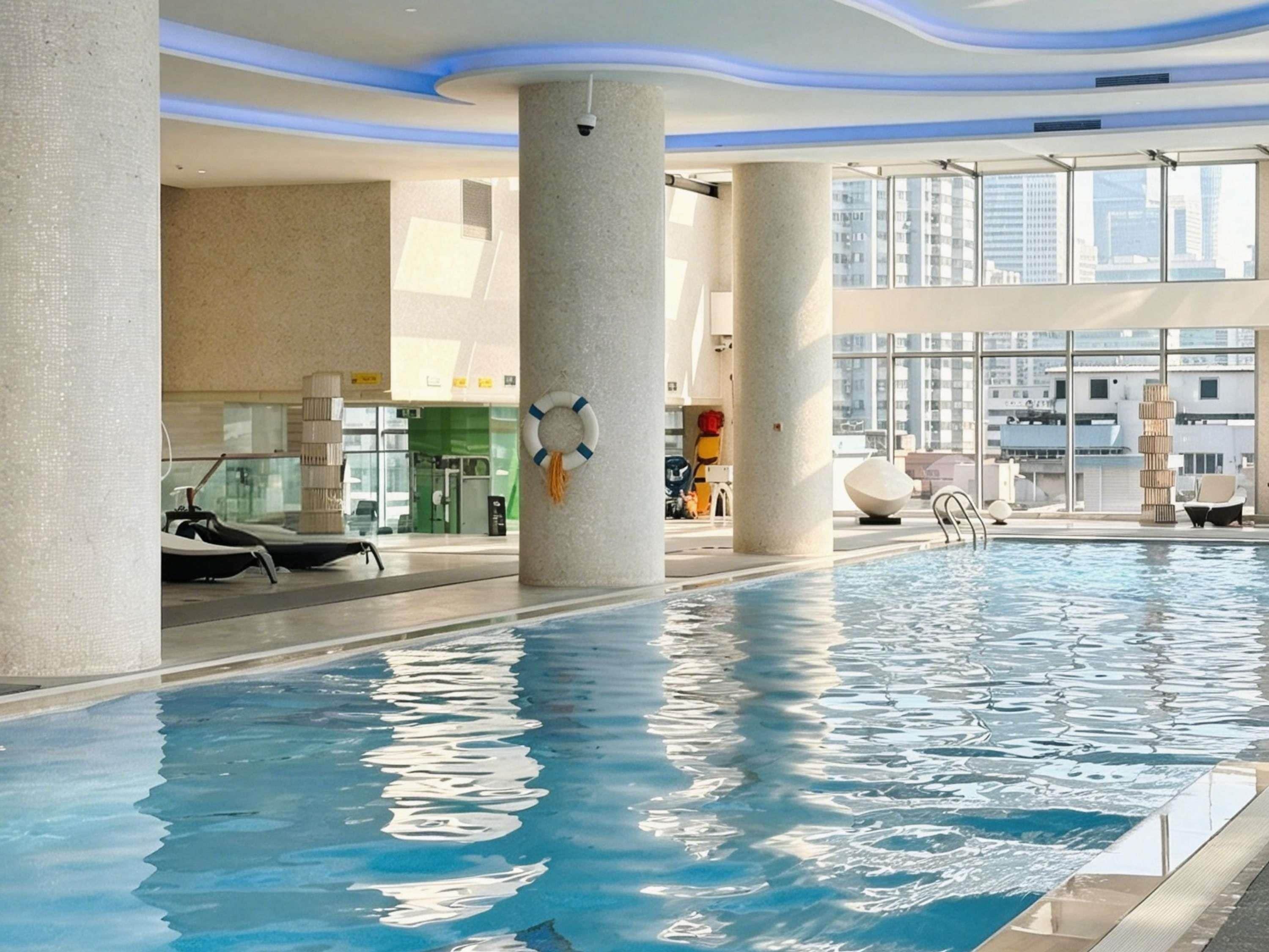 Een binnenzwembad met helder water, omgeven door kolommen en moderne architectuur.