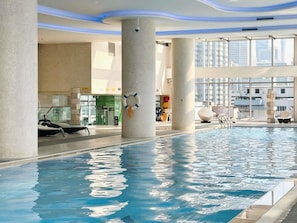 Una piscina interior con agua cristalina, rodeada de columnas y arquitectura moderna.