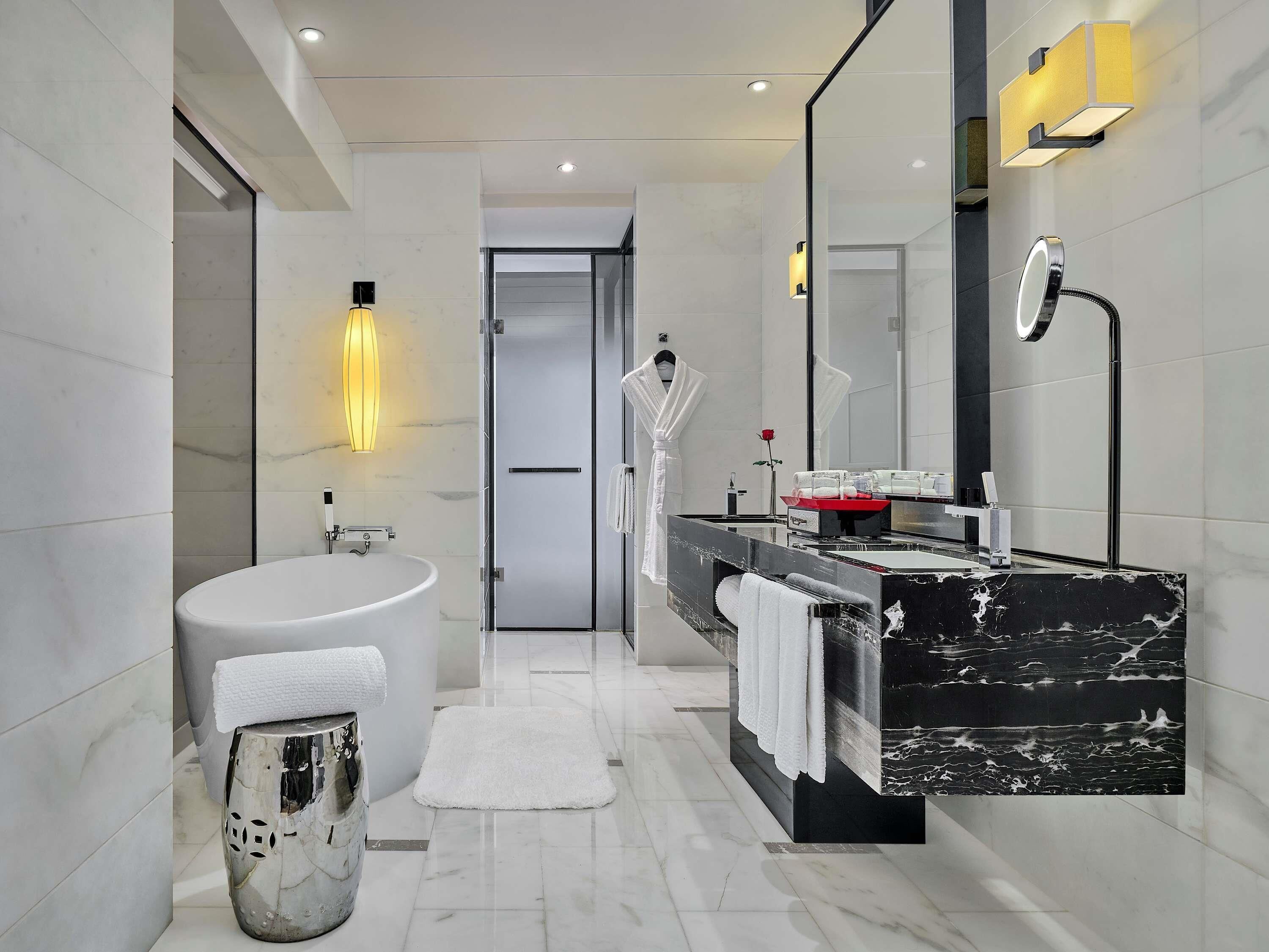 A modern bathroom with a large sink, a bathtub, a vanity with a mirror, and a shower area.
