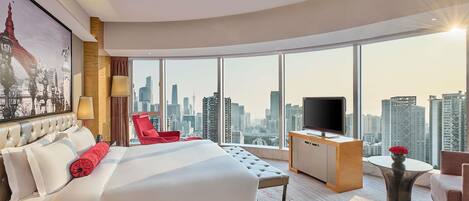 Una habitación de hotel moderna con una cama grande, una silla roja, un televisor y vistas a la ciudad.