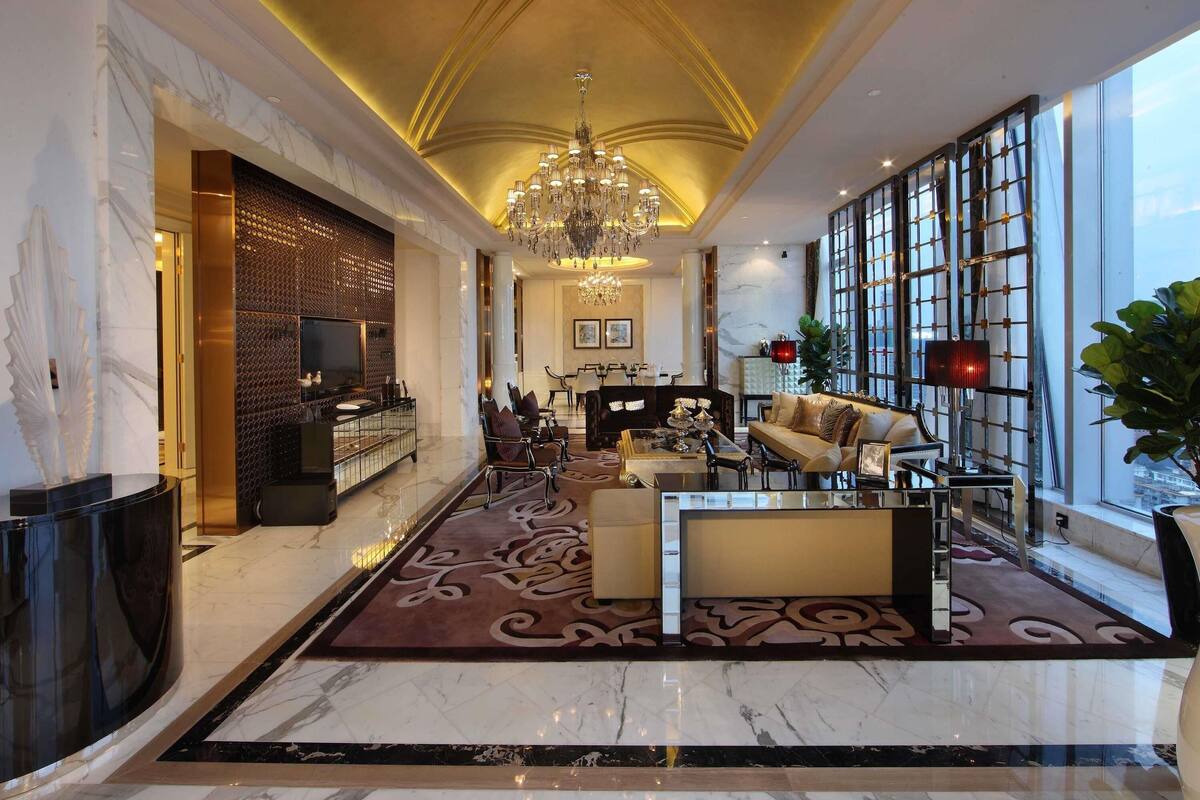 A spacious lobby with a marble floor, a chandelier, a sofa, and a large window with a view.