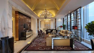 A spacious lobby with a marble floor, a chandelier, a sofa, and a large window with a view.