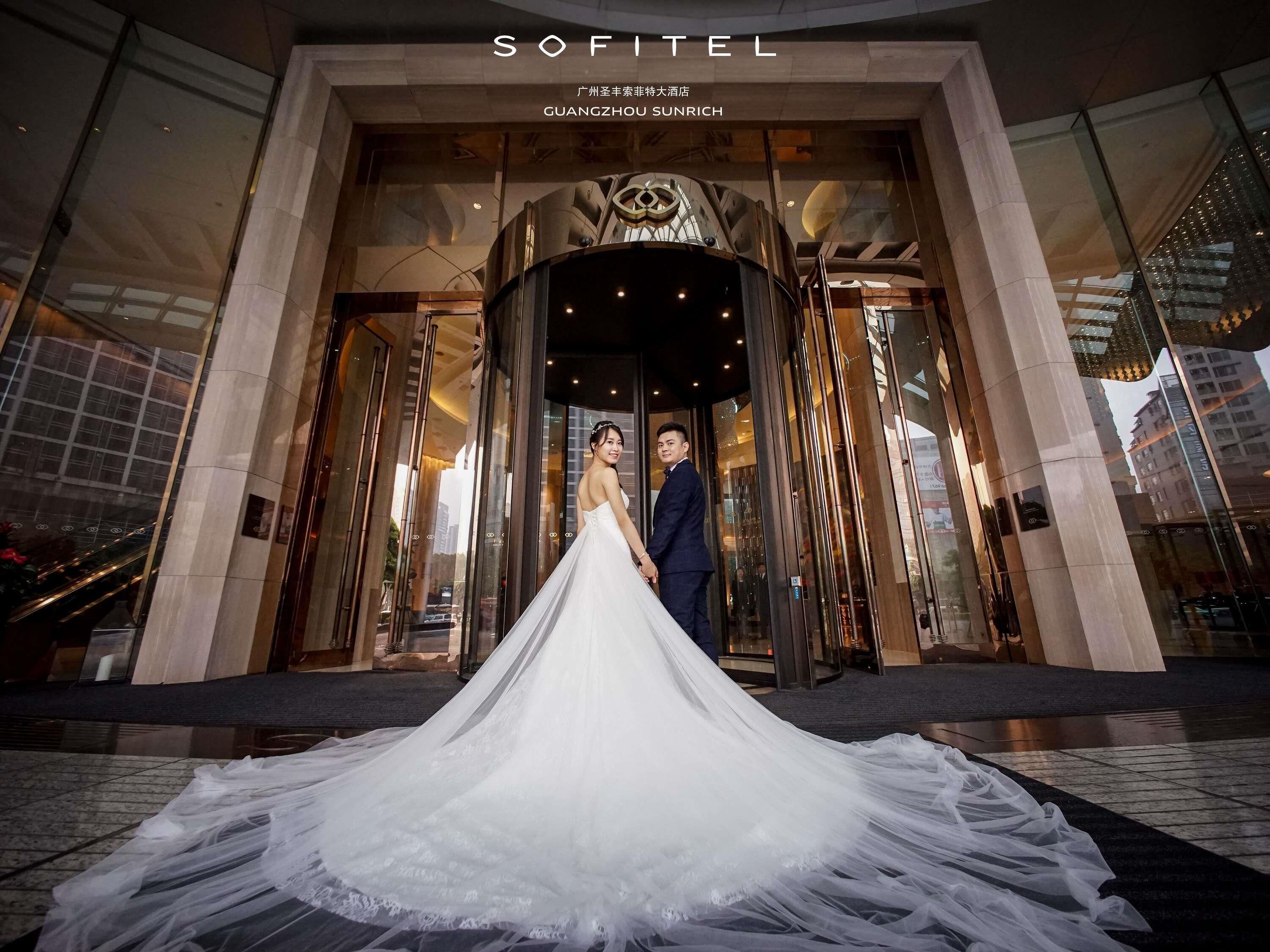A modern building entrance with glass doors and a large, ornate light fixture above.