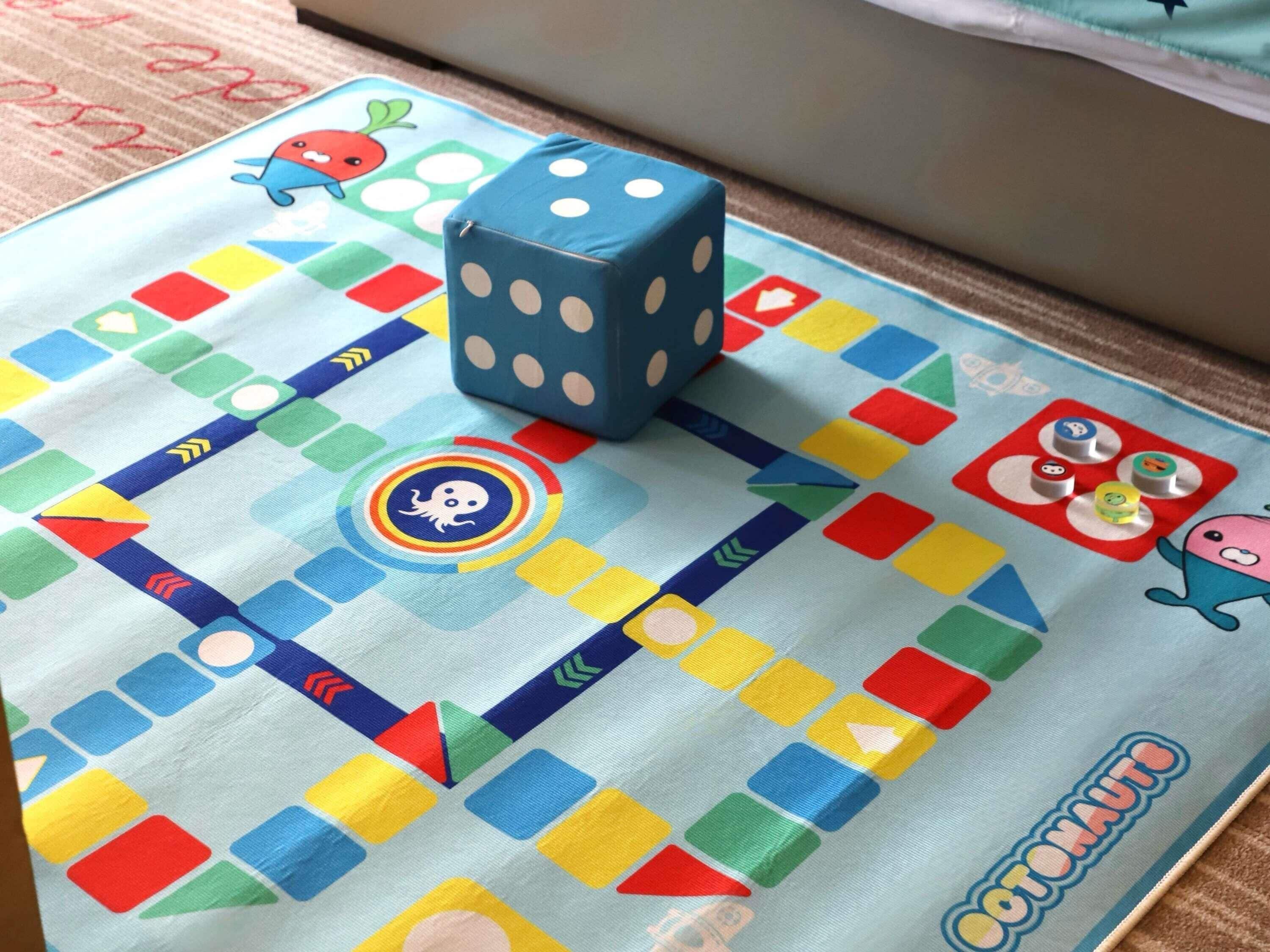 Un juego de mesa con casillas de colores y dados sobre una superficie de tela.