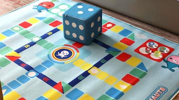 Un juego de mesa con casillas de colores y dados sobre una superficie de tela.