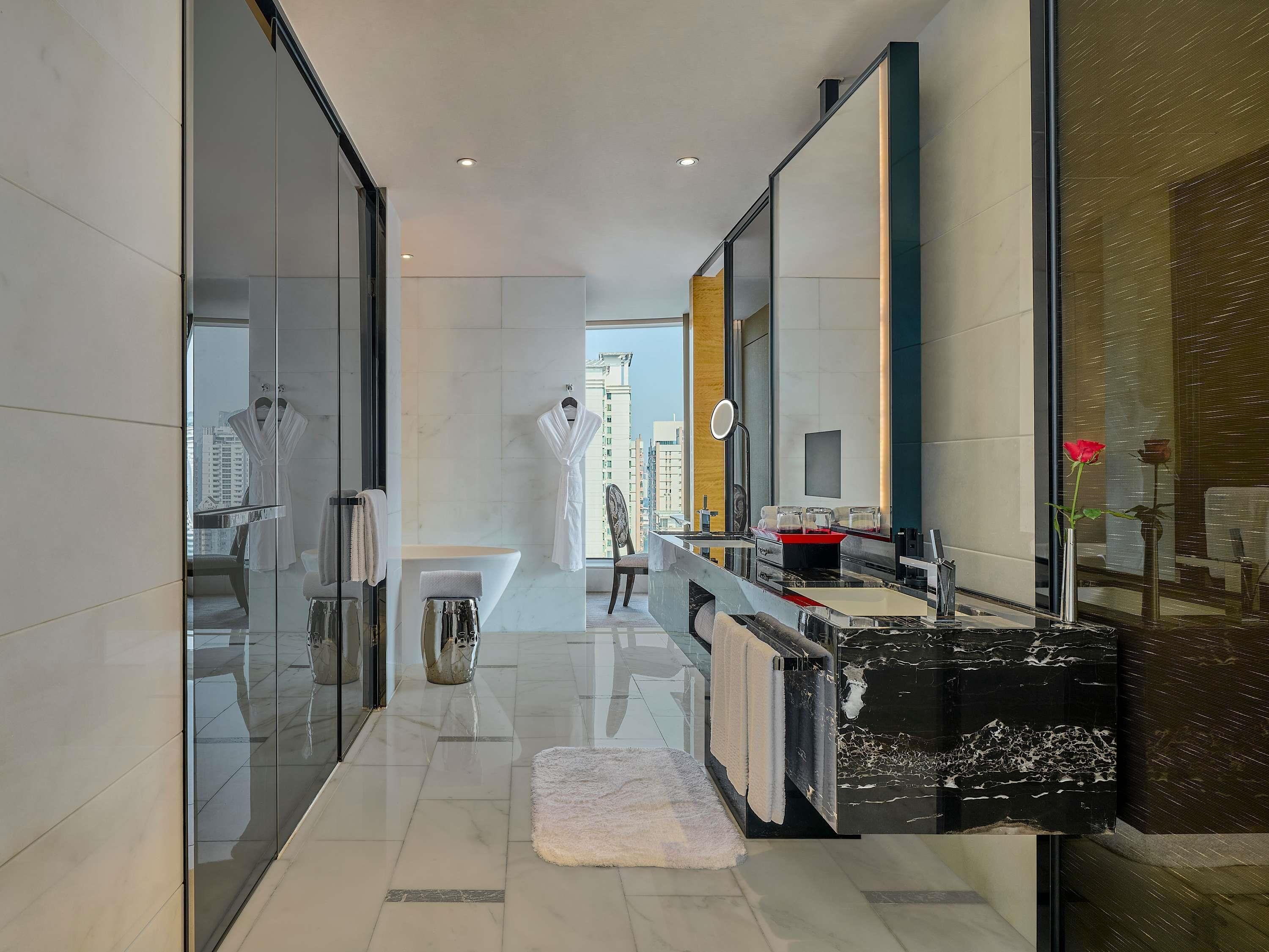 A modern bathroom with a glass shower enclosure, a marble sink, and a large mirror.