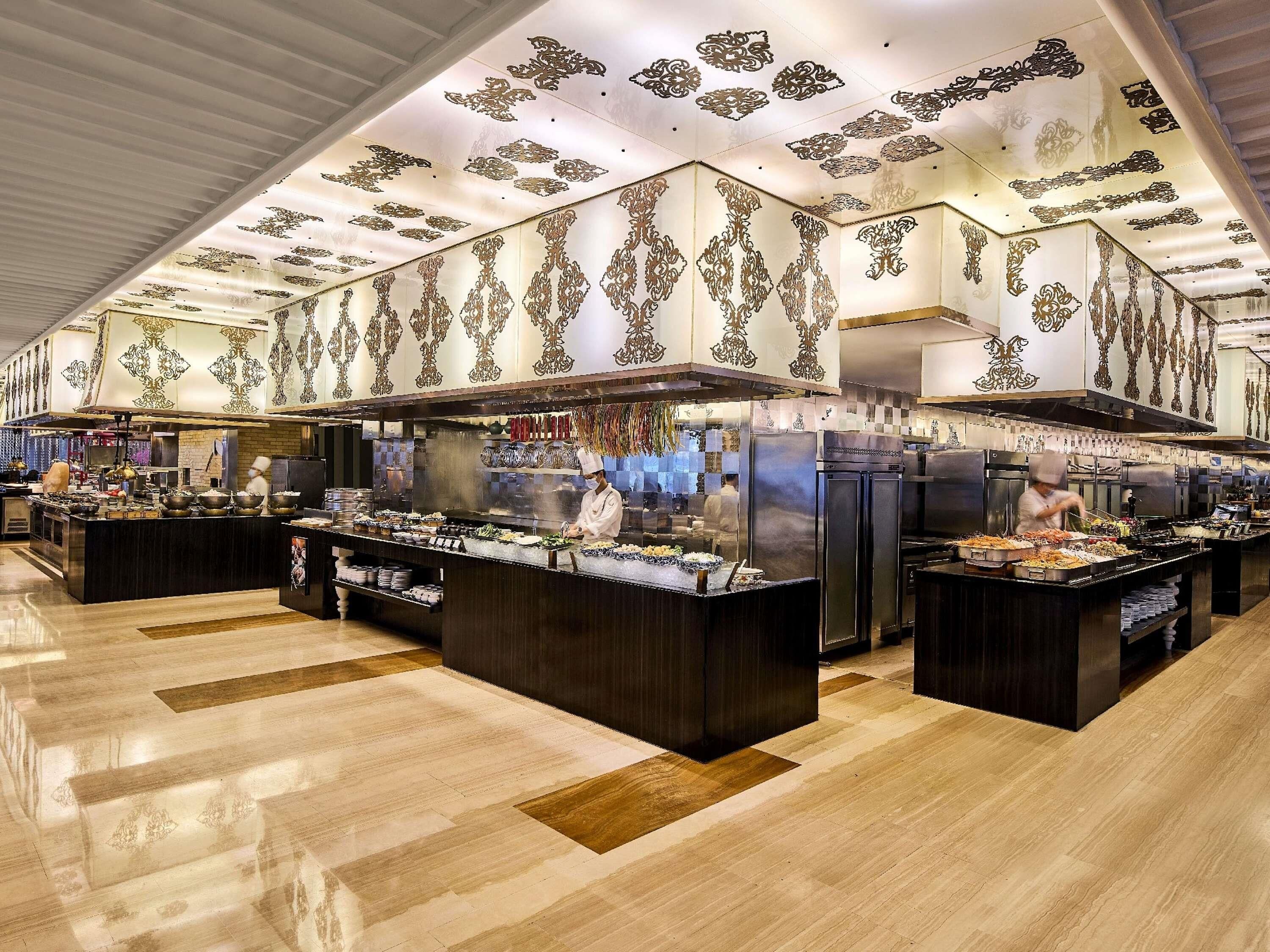 A spacious kitchen with multiple counters, chefs at work, and decorative ceiling patterns.