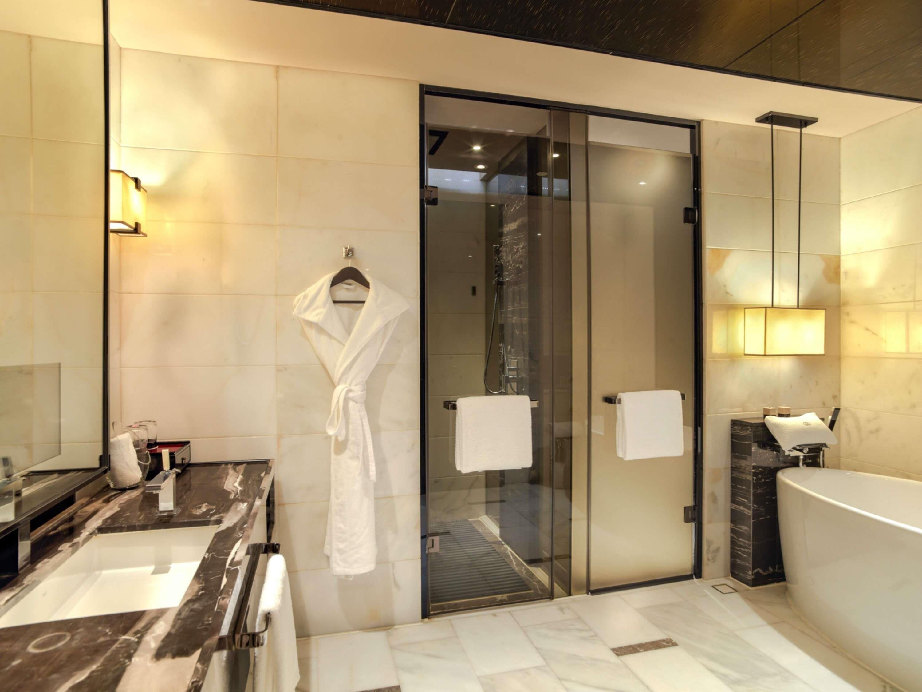 A modern bathroom with a glass shower enclosure, a bathtub, and a vanity with a mirror.