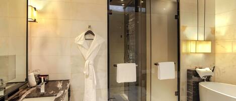 A modern bathroom with a glass shower enclosure, a bathtub, and a vanity with a mirror.
