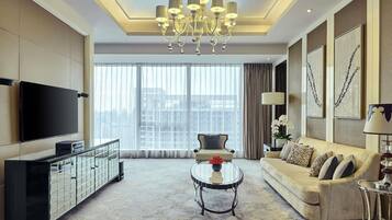 A modern living room with a large flat-screen TV, a sofa, a coffee table, and a chandelier.