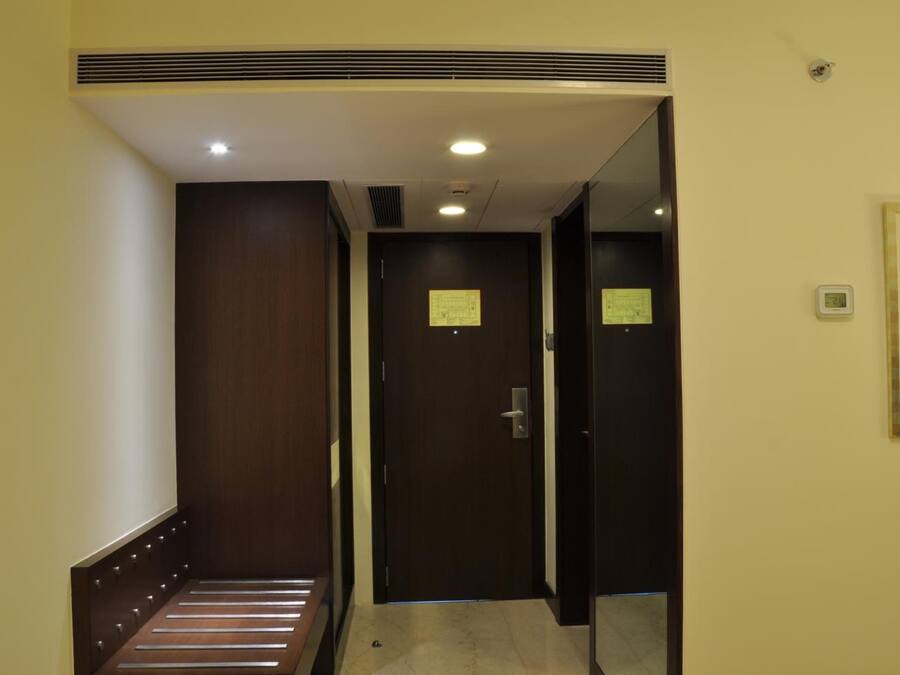 A narrow hallway with a wooden bench on the left, a door with a notice on it, and a framed picture on the wall.