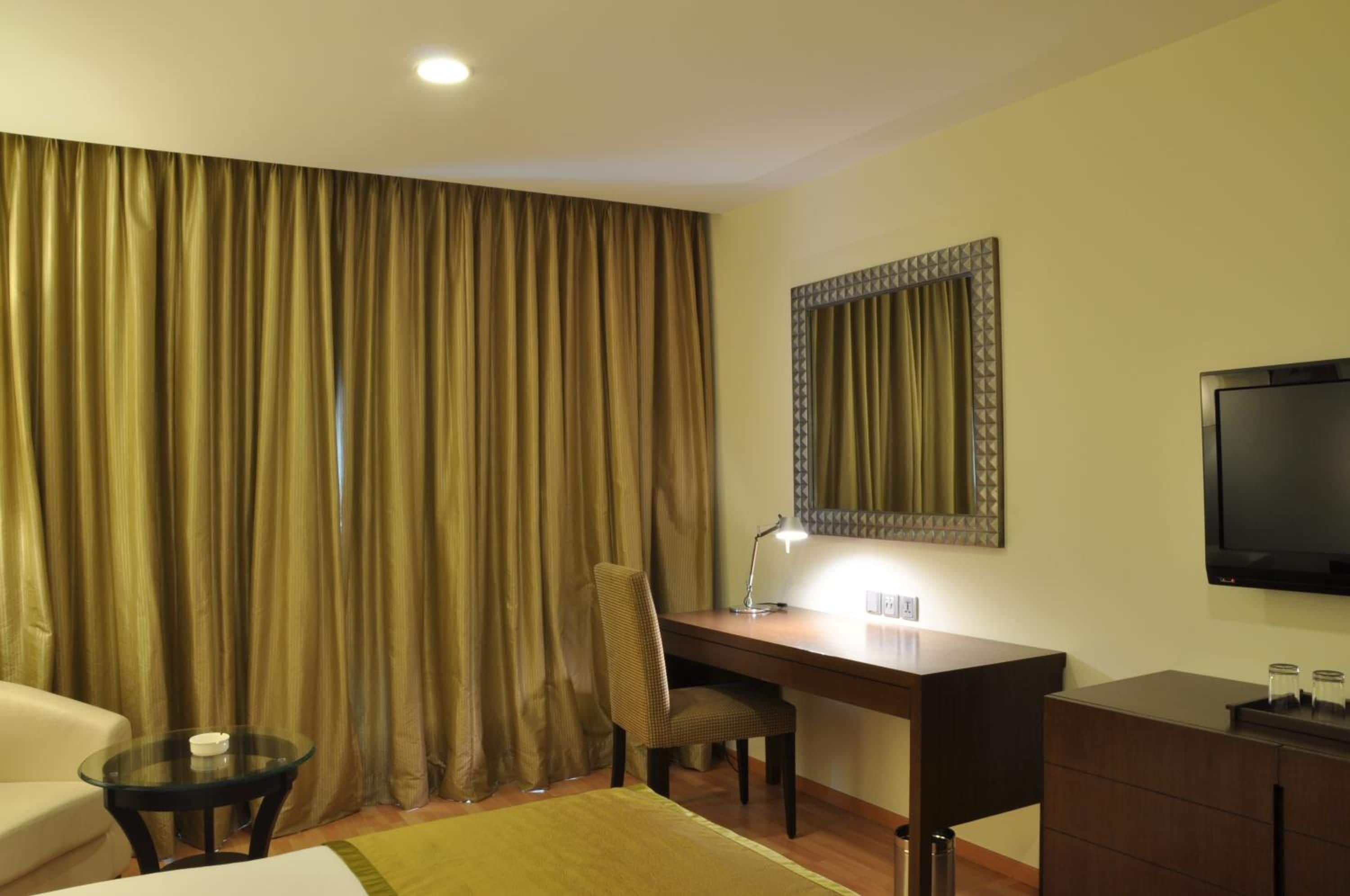 A hotel room with a desk, chair, television, and a bed.