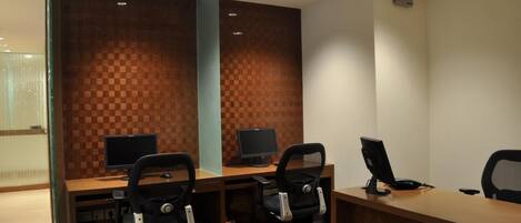 A reception area with a wooden checkered wall, two computer monitors, and three office chairs.