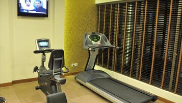 Un gimnasio con equipo cardiovascular, una caminadora y una bicicleta estática.