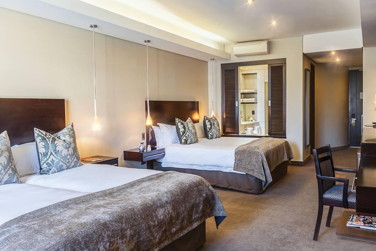 Ein Hotelzimmer mit zwei Betten, einem Schreibtisch und einem Stuhl.