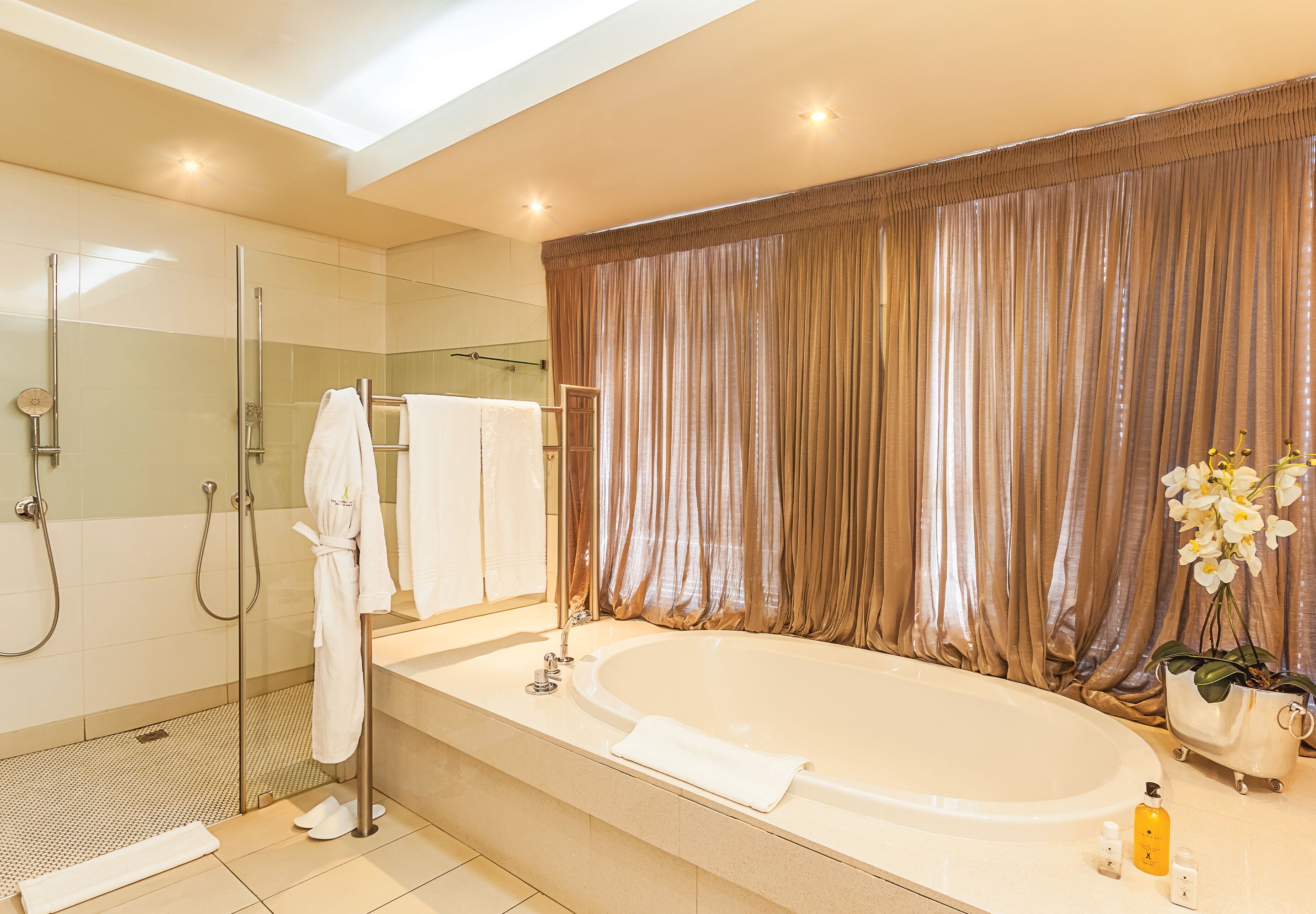 Un baño moderno con ducha de vidrio, una bañera grande y un tocador con espejo.