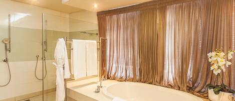 A modern bathroom with a glass-enclosed shower, a large bathtub, and a vanity with a mirror.