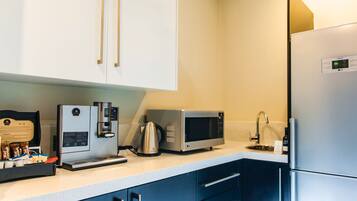 A kitchen with a coffee machine, microwave, and refrigerator.