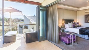 Ein modernes Hotelzimmer mit Balkon, einem Bett, einem kleinen Tisch und einer Couch.