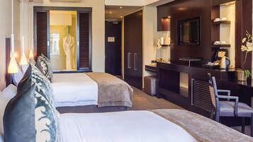 Hotelkamer met twee bedden, een bureau, een stoel, een televisie en een badkamer met een badjas.
