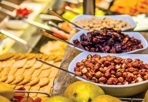 Un buffet proposant une variété d’aliments, notamment des fruits secs, des fruits frais et des pâtisseries.