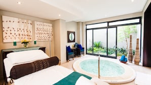 Ein modernes Hotelzimmer mit einem großen Bett, einer kleinen Sitzecke, einer privaten Whirlwanne und einem großen Fenster mit Blick ins Freie.